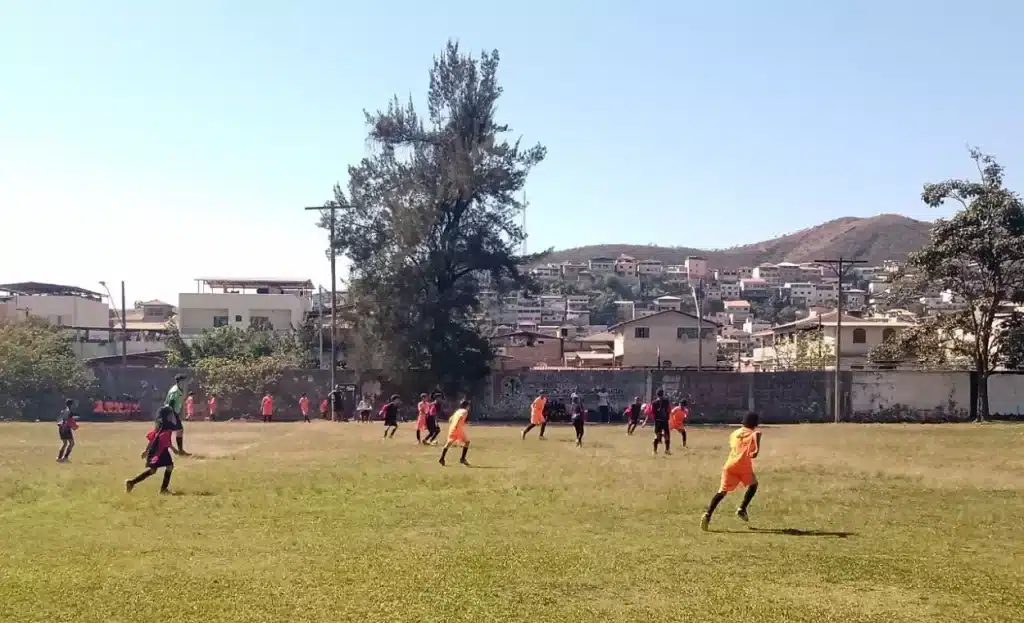 Jogadores mirins do CVRD, de camisas pretas e vermelhas,e União, de camisas cor de laranja, disputam patida de futebol que garante vaga na semifinal da categoria sub-11