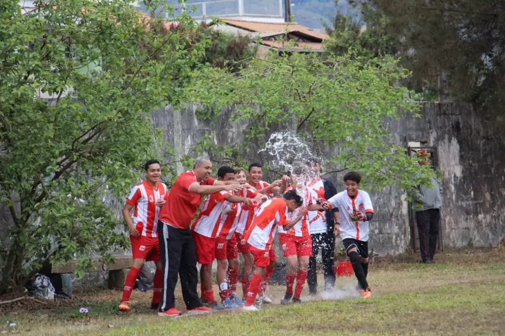 Atletas mirins do 1º de Maio, jogam água sobre um colega, na vitória que garantiu a presença na equipe nas finais do futebol de base de Mariana