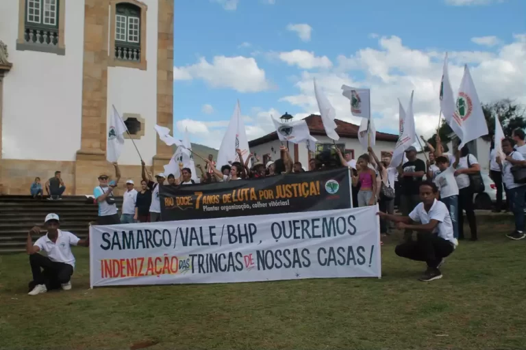 Na Praça Minas Gerais, participantes da marcha dos Atingidos portam bandeiras e faixa reclamando por seus direitos