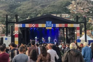 Público assiste a apresentação no palco do Festival Fado em Cidades Históricas em Ouro Preto, cercado por montanhas e casas históricas.