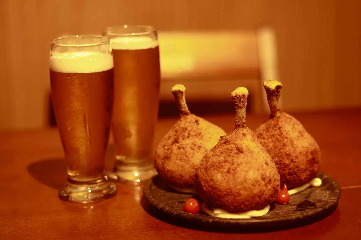 a foto mostra dois copos de cerveja ao lado de um prato com três coxinhas, as coxinhas são o prato escolhido pelo Bar Garden Beer, para participar do 1º festival Botecando, de Mariana