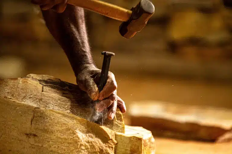 a imagem mostra uma pessoa quebrando pedra na escola de oficios tradicionais de mariana